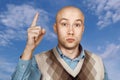 Portrait Bald serious man points and threatens with forefinger on blue sky background Royalty Free Stock Photo