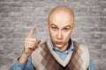 Portrait Bald serious man points and threatens with forefinger on brick wall white background Royalty Free Stock Photo