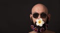 Unshaven man with beard with flowers and sunglasses on dark background with copyspace Royalty Free Stock Photo