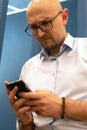 bald young businessman with glasses, staring at phone Royalty Free Stock Photo