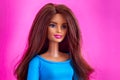 Portrait of Barbie doll with brown hair against pink background