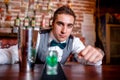 Portrait of barman behind bar with cocktail tools and drinks