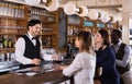 Portrait of barman and people who are standing near bar counter in luxurious restaurant Royalty Free Stock Photo