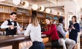 Portrait of barman and people who are standing near bar counter in luxurious restaurant Royalty Free Stock Photo