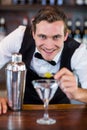 Portrait of bartender garnishing cocktail with olive