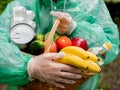 Portrait of a basket of food in the hands of a woman volunteer in protective gloves and rain coat, close-up.