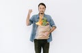 Portrait of beard young Asian man holding shopping paper bags full of groceries and showing biceps muscles isolated at white Royalty Free Stock Photo