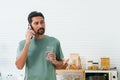 Portrait, Bearded Asian man wearing t-shirt on casual day. Standing in the kitchen talking on the mobile phone while waiting to Royalty Free Stock Photo