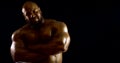 A bearded bald brutal male bodybuilder with a naked inflated torso, he is in the Studio on a black background, Posing Royalty Free Stock Photo