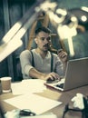 Portrait of a bearded businessman who is checking details of his upcoming meeting in his notebook and typing. Royalty Free Stock Photo