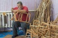 Portrait of bearded Caucasian senior master of wicker-work making kids chair