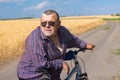 Portrait of a bearded, chubby Ukrainian senior man leant elbows to handle bar of his bicycle