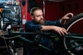 Portrait of bearded cycling mechanic male repairing and fixing mountain bicycle standing on bike rack working in bicycle Royalty Free Stock Photo