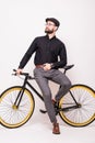 Portrait of a bearded handsome young man leaning on fixie bicycle over white background