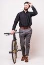 Portrait of a bearded handsome young man walking with fixie bicycle over white background