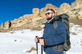 Portrait A bearded hipster with a backpack and in sunglasses with a large backpack on his shoulders stands with sticks