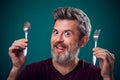 A portrait of bearded man holding spoon and fork in hands. People and food concept