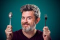 A portrait of bearded man holding spoon and fork in hands. People and food concept