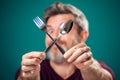 A portrait of bearded man holding spoon and fork in hands. People and food concept