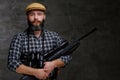 Portrait of a bearded hunter traveler in a fleece shirt and hat holds rifle with a sight and binoculars.