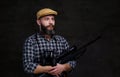 Portrait of a bearded hunter traveler in a fleece shirt and hat holds rifle with a sight and binoculars.