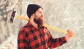 Portrait of a bearded lumberjack. Lumberjack in the woods with an ax. Bearded man in hat with a hatchet. Handsome man