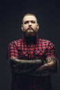 Portrait of bearded male with crossed tattooed arms.