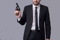 Portrait of a bearded man in a business suit holding a revolver. On a gray background Royalty Free Stock Photo