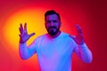 Portrait of bearded man in casual clothes posing with misunderstanding face against gradient studio background in neon Royalty Free Stock Photo