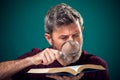 A portrait of bearded man holding opened book and magnifying glass. People, education and searching concept Royalty Free Stock Photo