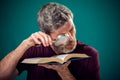 A portrait of bearded man holding opened book and magnifying glass. People, education and searching concept Royalty Free Stock Photo