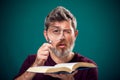 A portrait of bearded man holding opened book and magnifying glass. People, education and searching concept Royalty Free Stock Photo