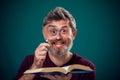 A portrait of bearded man holding opened book and magnifying glass. People, education and searching concept Royalty Free Stock Photo