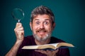 A portrait of bearded man holding opened book and magnifying glass. People, education and searching concept Royalty Free Stock Photo