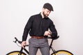 Portrait of a bearded man leaning on fixie bicycle and looking at watch over white background