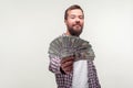 Portrait of bearded man looking arrogant at camera and showing money giving dollars to camera. white background