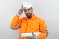 Worker builder wearing hardhat holding plans under arm