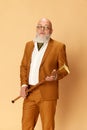 Portrait of bearded, mature, bald man in elegant, classical suit posing with serious expression against studio