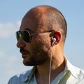 portrait of a bearded mature man wearing sunglasses with headphones, closeup.