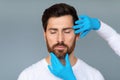 Portrait of bearded middle aged man getting prepared for plastic surgery procedures, doctor touching male face skin Royalty Free Stock Photo