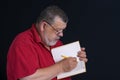 Portrait of a bearded senior writing a letter to his son in notebook