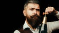 Portrait of a bearded waiter holding a champagne bottle. Close up portrait of man uncorking a bottle of champagne