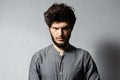 Portrait of bearded young guy with disheveled hair, looking angry at camera, on background of grey. Royalty Free Stock Photo