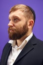 Portrait of bearded young Jewish man in yarmulke posing against purple studio background Royalty Free Stock Photo