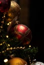 A portrait of a beautifful red glass christmas ball with sparkling little diamonds on it hanging in a christmas tree. The holiday