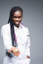 Portrait of beautiful African American doctor or nurse holding prescription drugs isolated over gray background Royalty Free Stock Photo