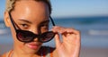 Beautiful woman looking over sunglasses on beach in the sunshine Royalty Free Stock Photo