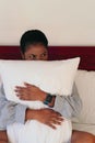 Portrait of a beautiful African woman covering her body with a pillow in bedroom Royalty Free Stock Photo