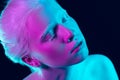 Portrait of beautiful albino girl on dark studio background in neon light