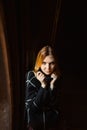 Portrait of a beautiful angry blonde woman in a black sweater sitting on an old windowsill in the dark. Horror Royalty Free Stock Photo